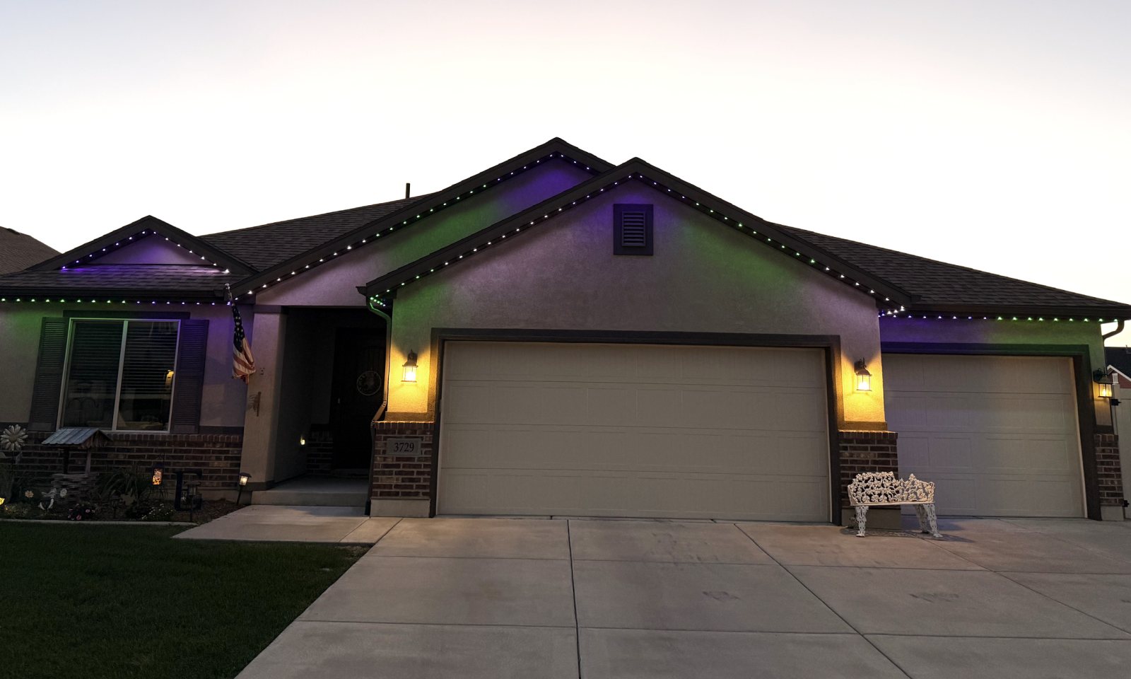 After: the same rambler at dusk with its roofline lit in green and purple