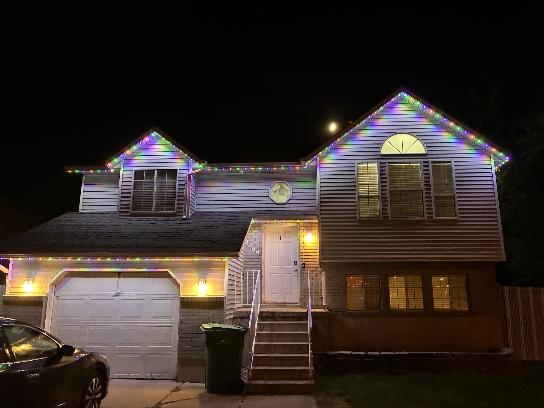 The same two-story home with multicolor bulbs in green, purple and orange