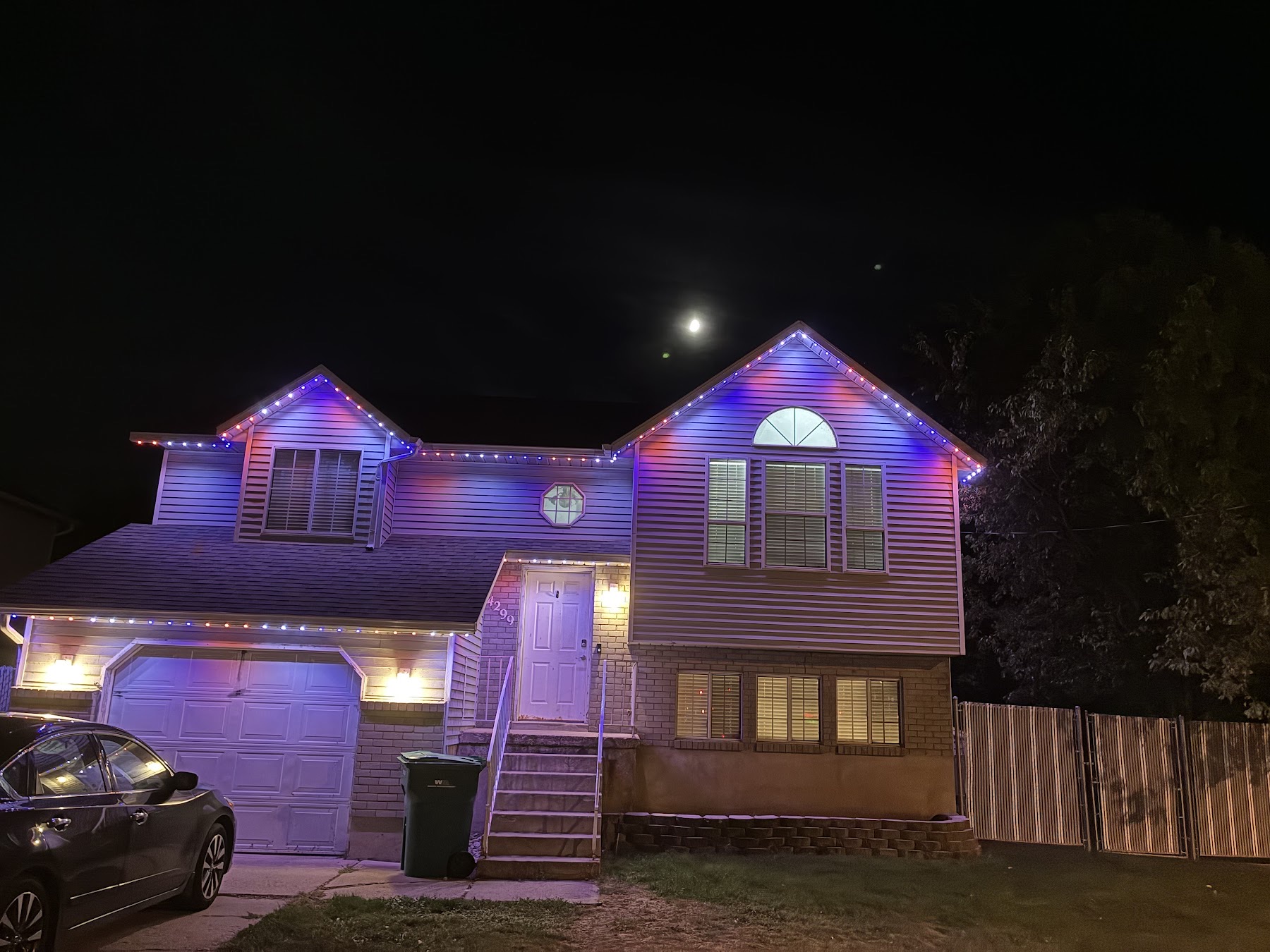 The same two-story home with pink and blue light fading across the gables